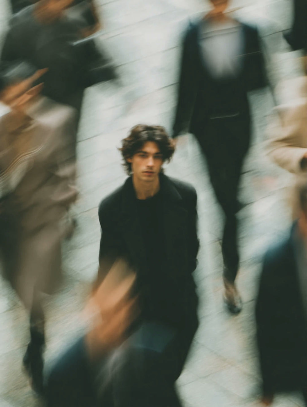 A man standing still in a blurred, moving crowd